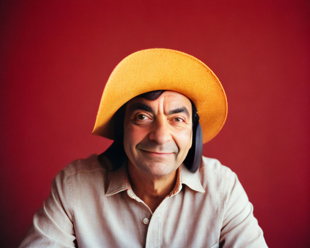 Smiling man in large yellow hat on red background