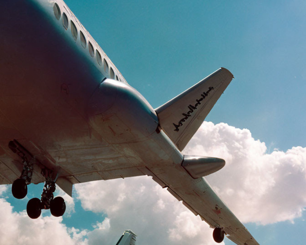 Low angle view of airplane with extended landing gear against blue sky.