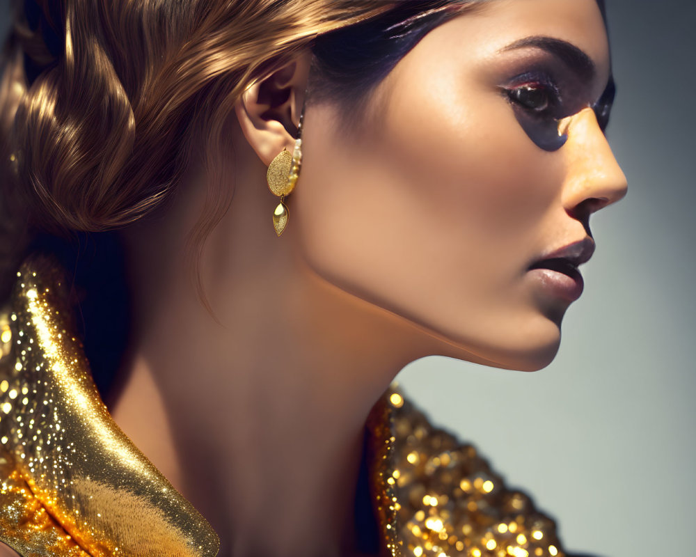 Woman's side profile with elegant hairstyle, golden makeup, and matching glittering earrings.