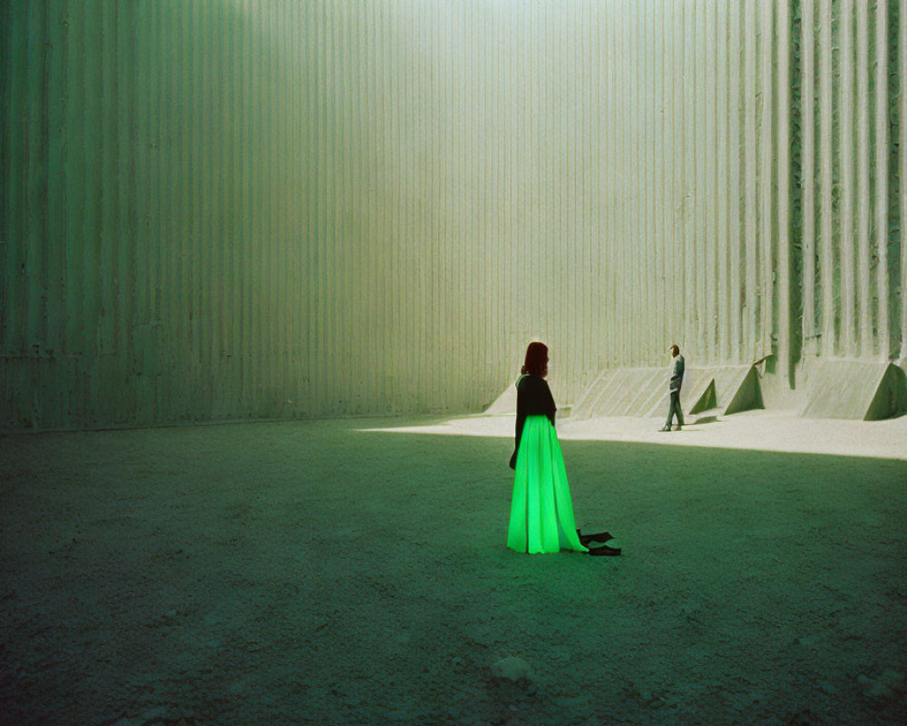 Woman in Green Dress Standing in Sunlit Space with Tall Ridged Walls