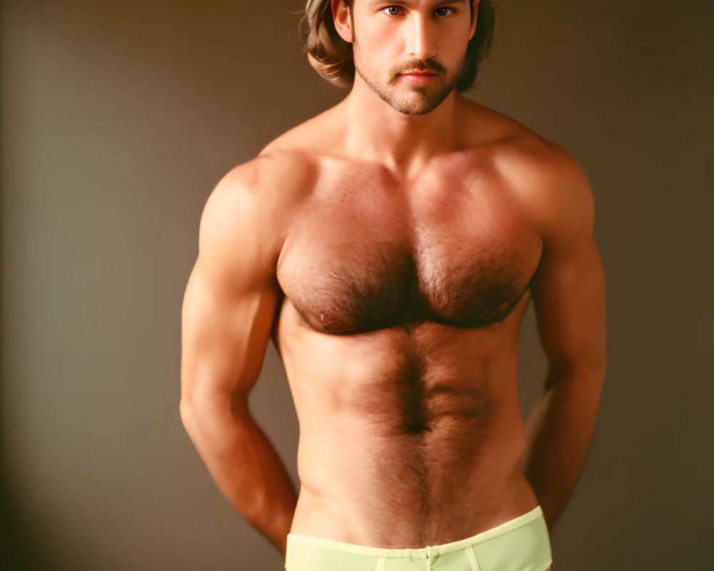 Muscular man in yellow briefs against brown background