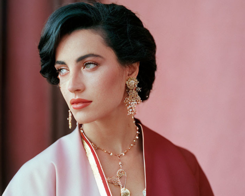 Dark-haired woman in pink robe and red lipstick against pink backdrop
