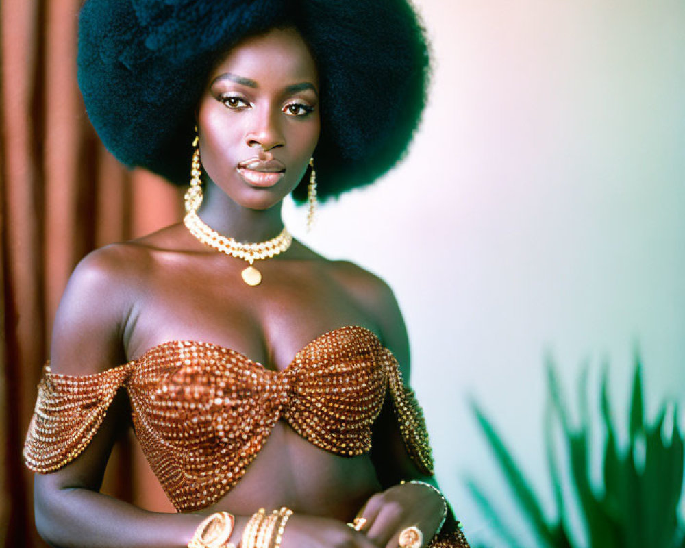 Elegant person with voluminous afro in golden dress poses with plant