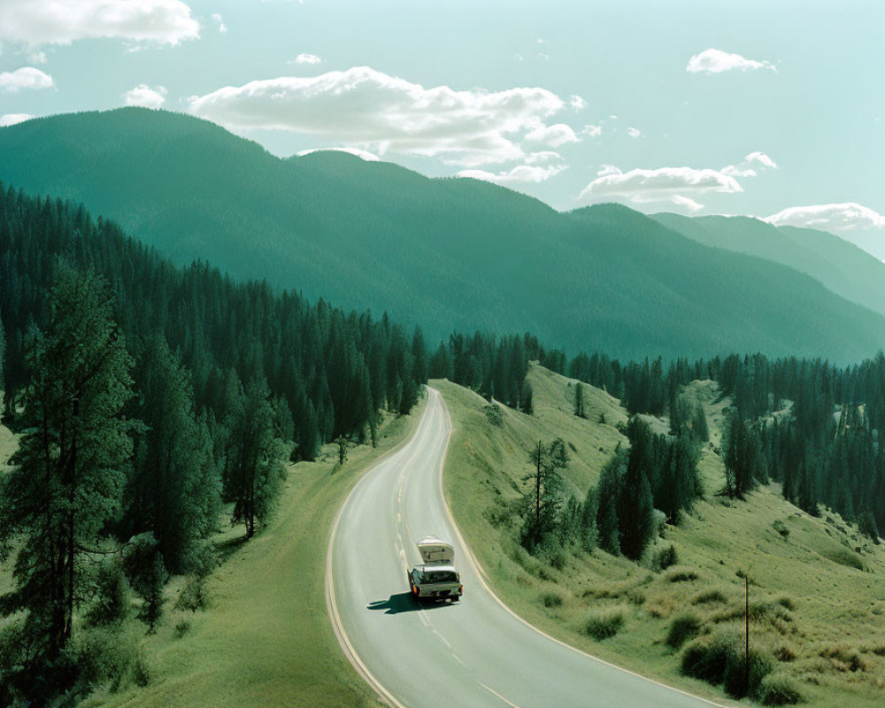 Scenic image of car on winding road through lush green landscape