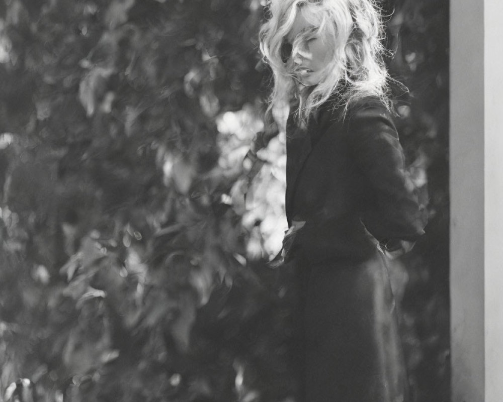 Monochrome photo of contemplative person with wavy hair outdoors