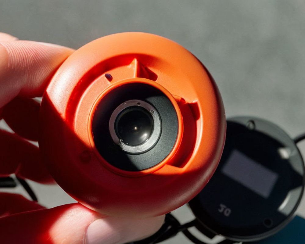 Close-Up of Hand Holding Red Portable Camera with Small Lens