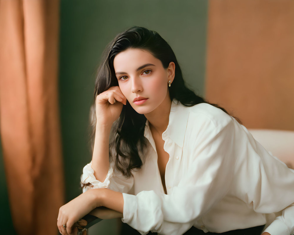 Dark-haired woman in white shirt gazes pensively at camera