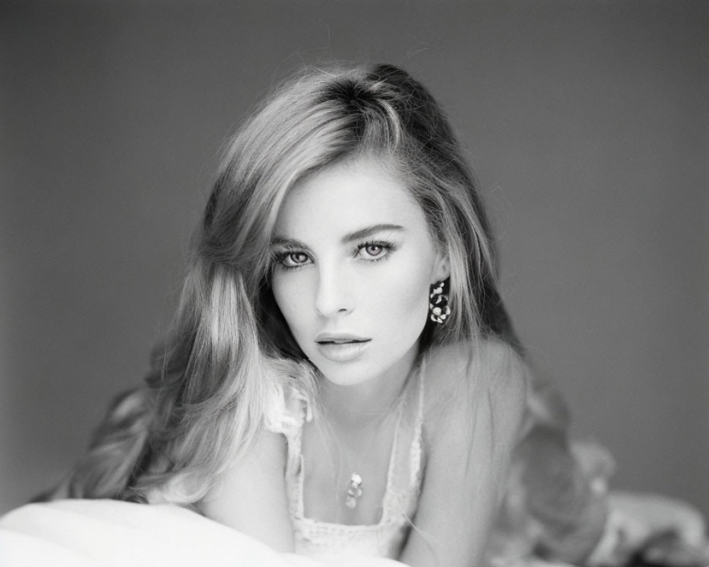 Monochrome portrait of woman with intense gaze and elegant jewelry.