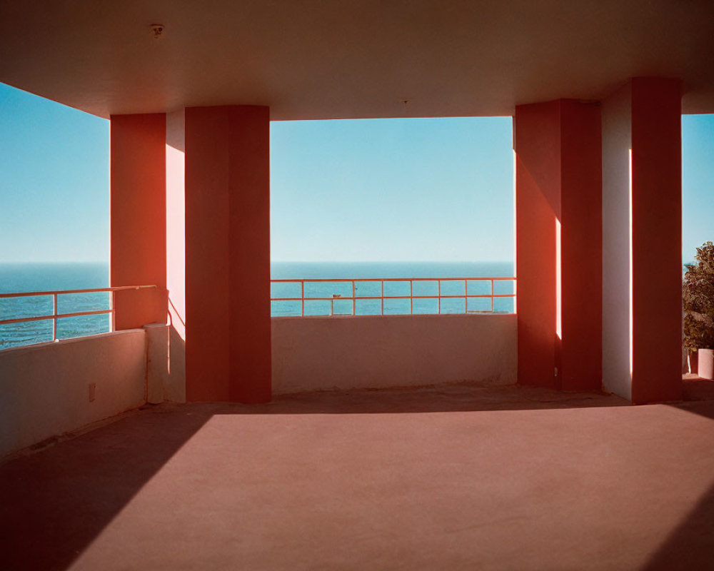 Red-pillared balcony overlooking sea under blue sky