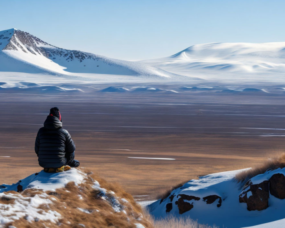 Snow-covered landscape with undulating hills under a clear blue sky