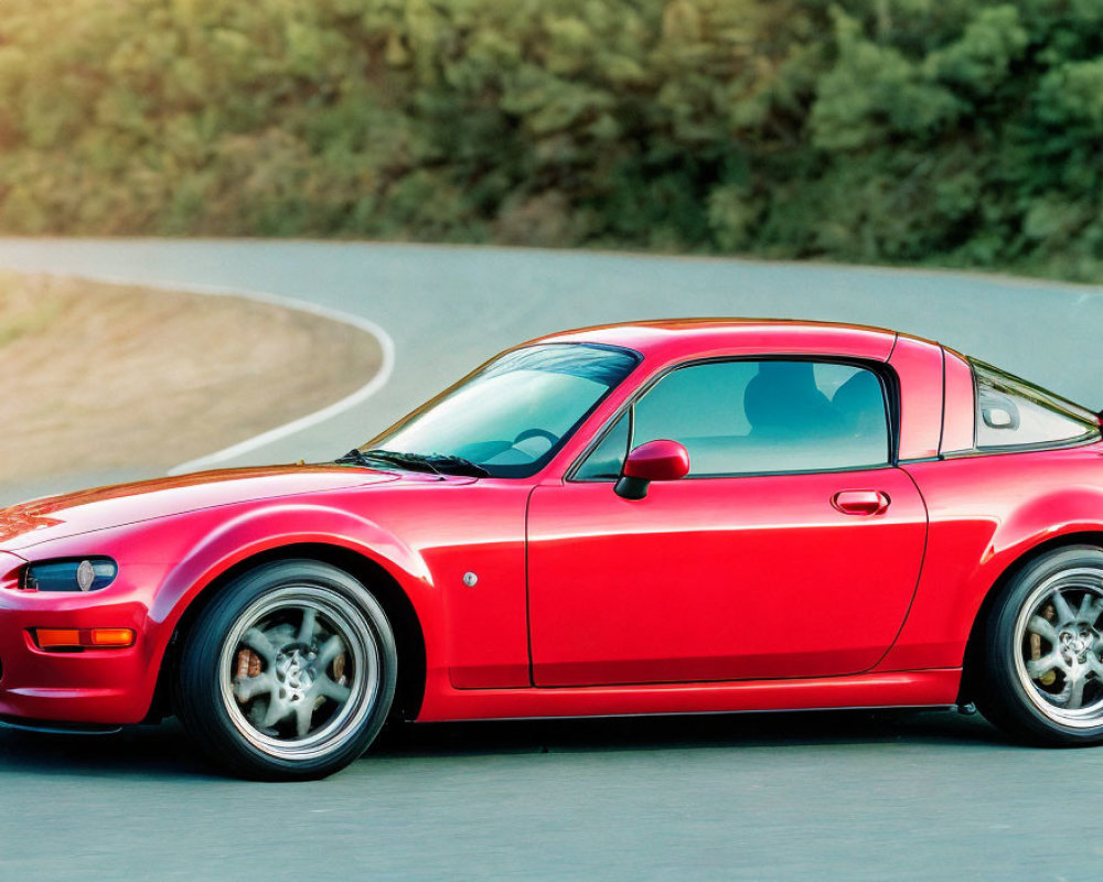 Red Sports Coupe with Silver Rims on Winding Road Amid Blurred Greenery