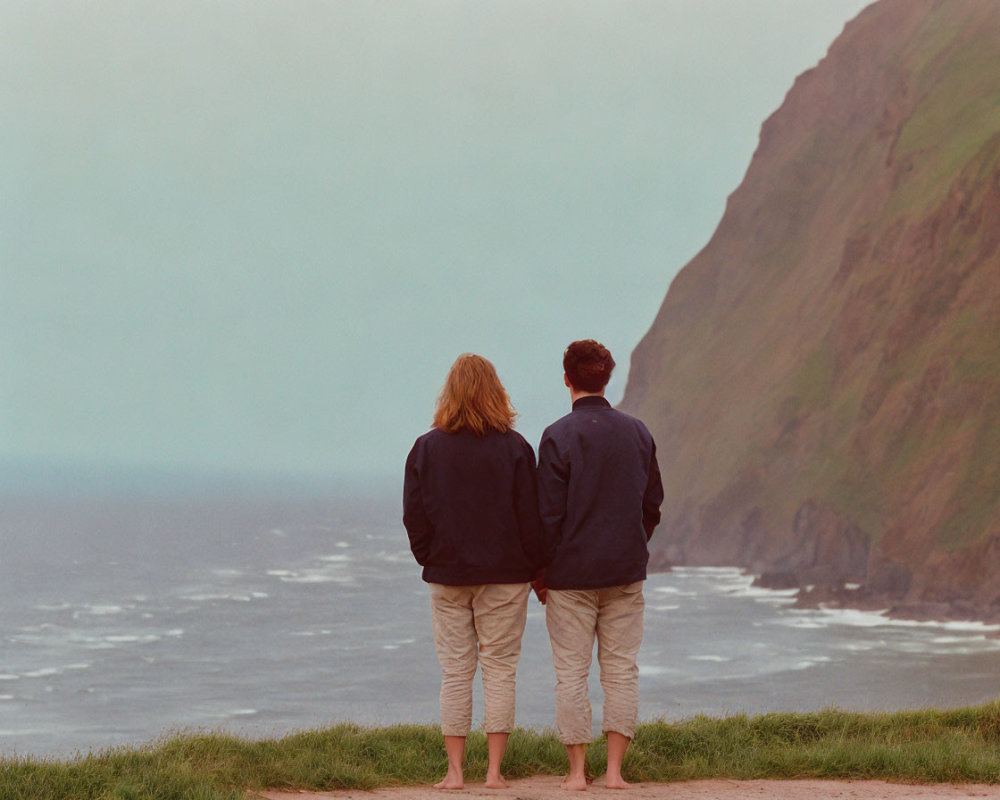 Couple on Cliff overlooking Sea with Cloudy Sky