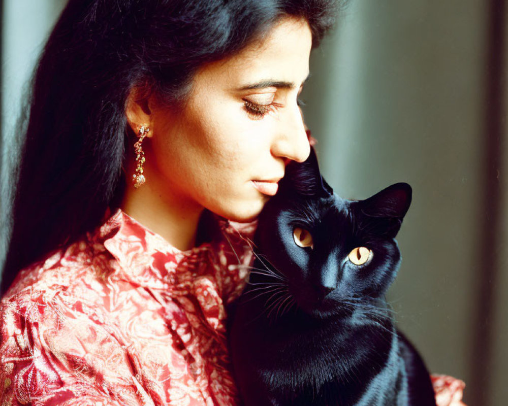 Woman with long dark hair holding black cat with yellow eyes