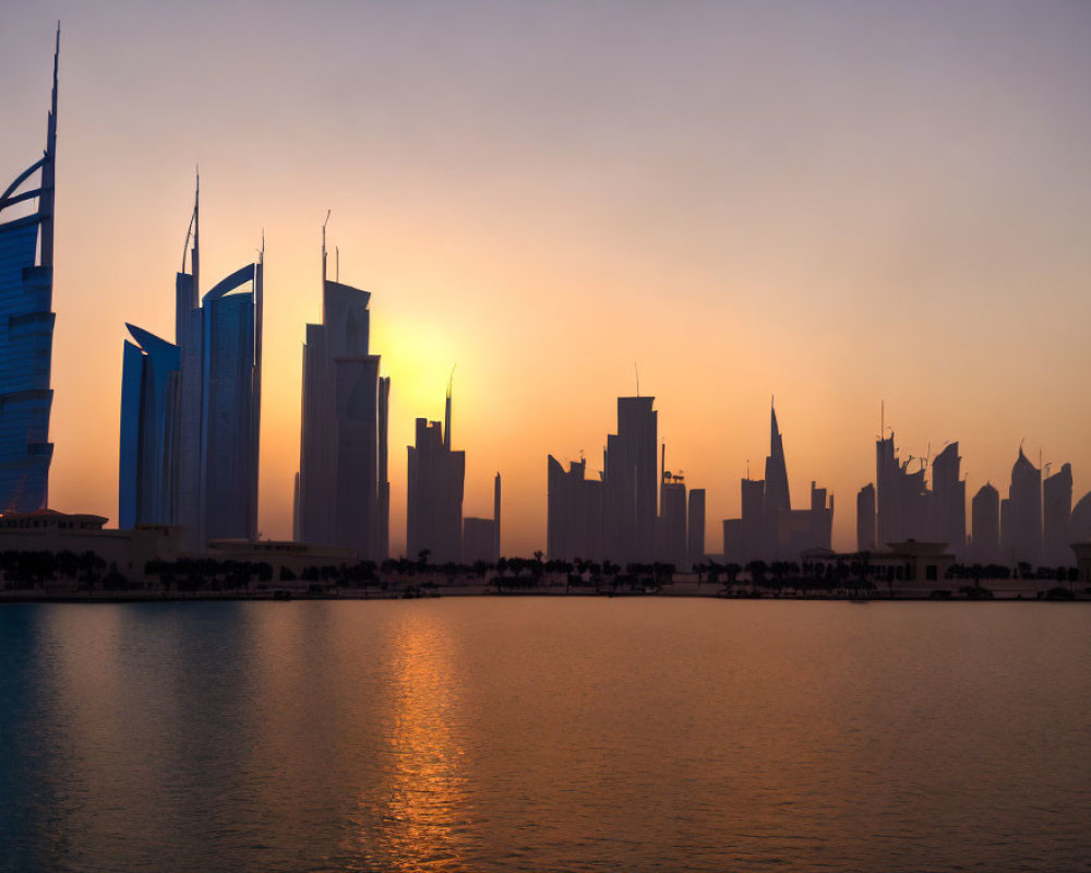 Modern city skyline silhouette against orange sunset sky reflected in water