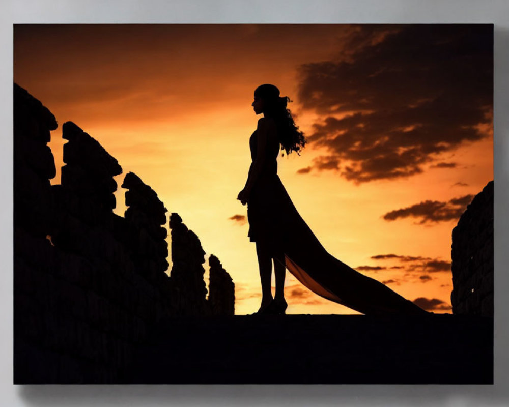Woman in Dress and Hat Silhouetted Against Orange Sunset Sky by Ancient Ruins