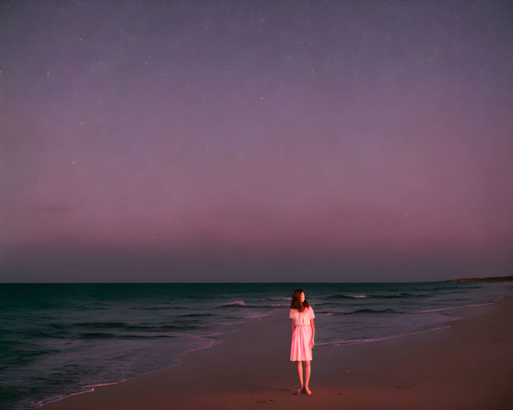 Person in Pink Dress on Beach at Twilight with Starry Sky and Calm Sea