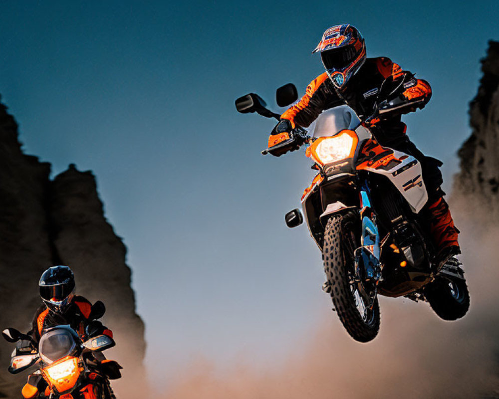 Motorcyclists performing jump against rocky backdrop