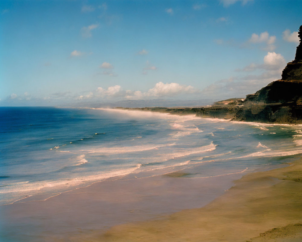 Vast beach, steep cliff, clear blue sky coastal landscape