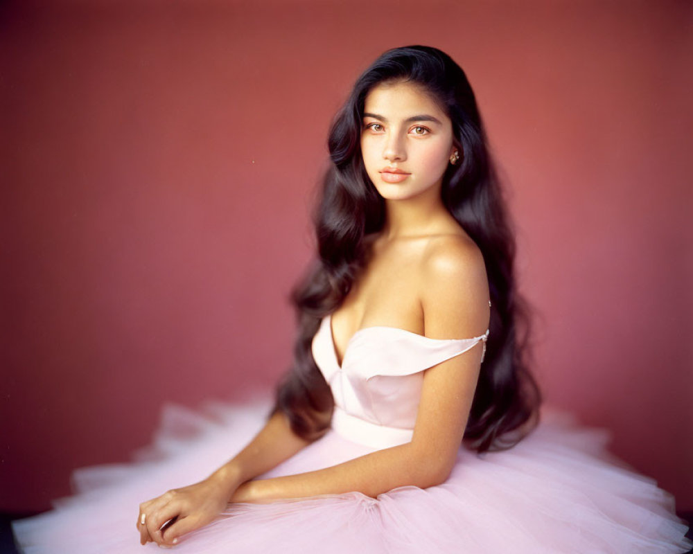 Young woman in pale pink strapless dress against maroon background