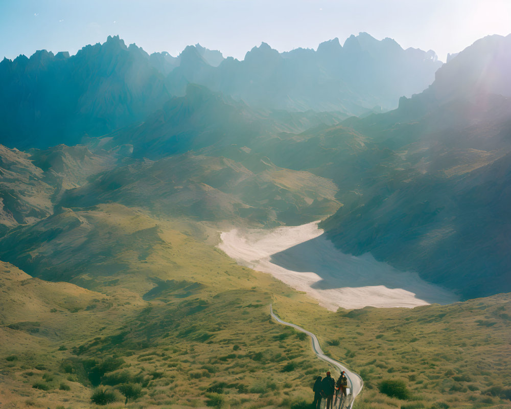 Scenic valley with winding path, horseback riders, sunlit mountains, and clear sky