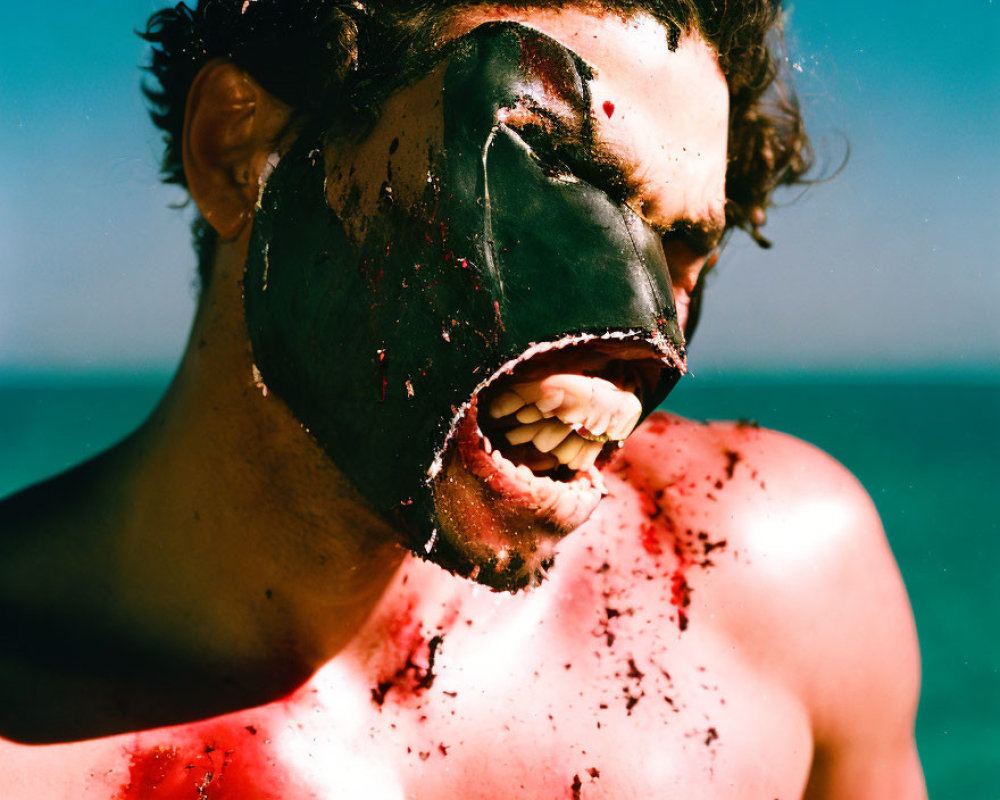Man wearing black face mask against blue ocean backdrop with blood-like splatters