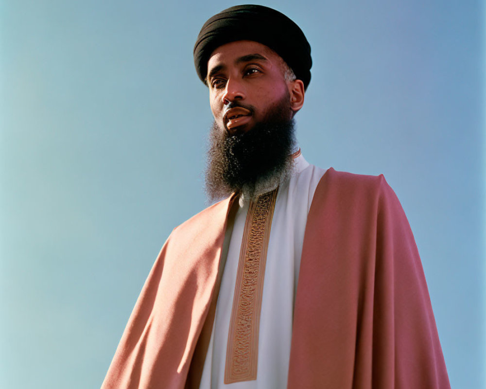 Bearded man in cap and embroidered robe against blue sky