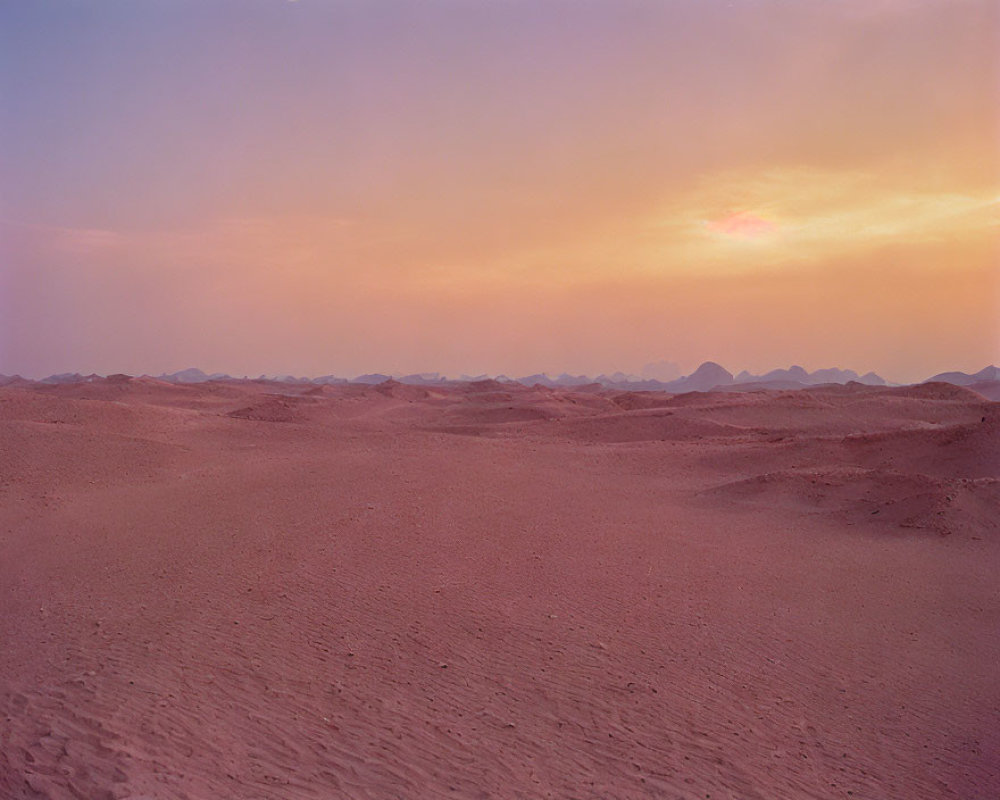 Tranquil desert landscape at dusk with rolling dunes and soft pink sunset glow