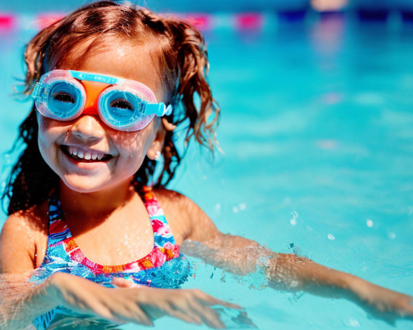 Smiling young girl in swimming pool with goggles