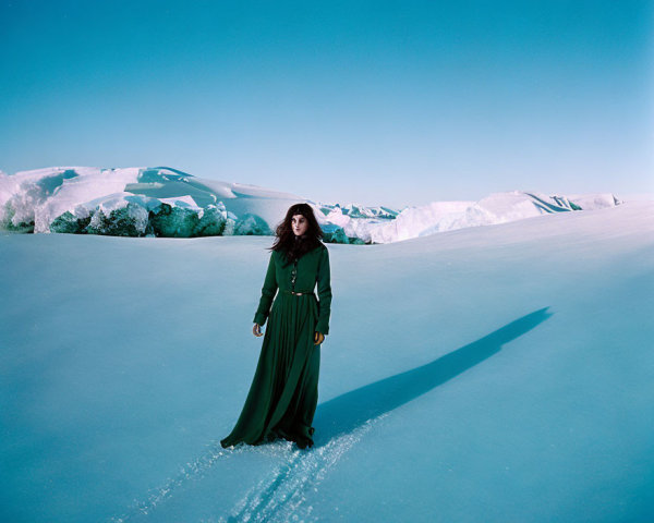 Woman in Long Green Dress Standing on Snow with Ice Stretch and Blue Sky